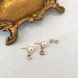 Pearl earrings on a white surface with a gold decorative object.