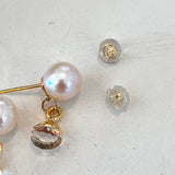 Pearl earring with gold accents on a light gray surface