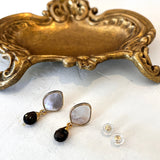 Pair of gold stud earrings with mother of pearl and smokey quartz on a white background