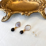 Pair of gold stud earrings with mother of pearl and smokey quartz on a white background