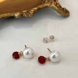 Pair of pearl earrings with carnelian on a white surface.