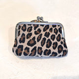 A small kiss-lock clutch purse with a leopard print pattern in black, brown, and beige, featuring a silver-tone metal frame and clasp.
