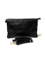 Black glittery clutch bag with a strap on a white background