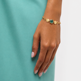 Raw Emerald and Vermeil bracelet on model's hand against an aqua background 
