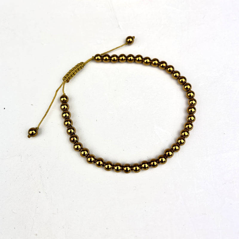 Gold beaded bracelet on a white background