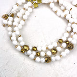 White and gold beaded bracelets on a white textured background