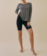 Person wearing a gray long-sleeve top and black shorts on a beige background