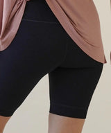 Person wearing black shorts with a pink top on a beige background
