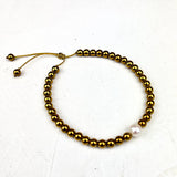 Gold beaded bracelet with a pearl on a white background