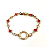 Gold bracelet with red clover-shaped links on a white background