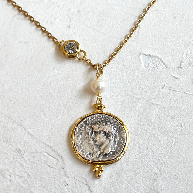 Necklace with a coin pendant and pearl on a white background