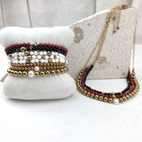 Set of beaded bracelets and a necklace on a white surface with a neutral background