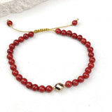 Red beaded bracelet with a gold clasp on a white background