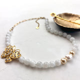 Beaded necklace with a gold butterfly pendant on a light surface