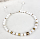 Bracelet with white and gold beads on a light background