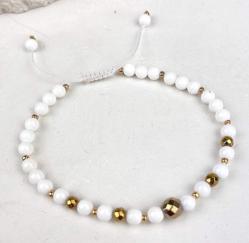 Bracelet with white and gold beads on a light background