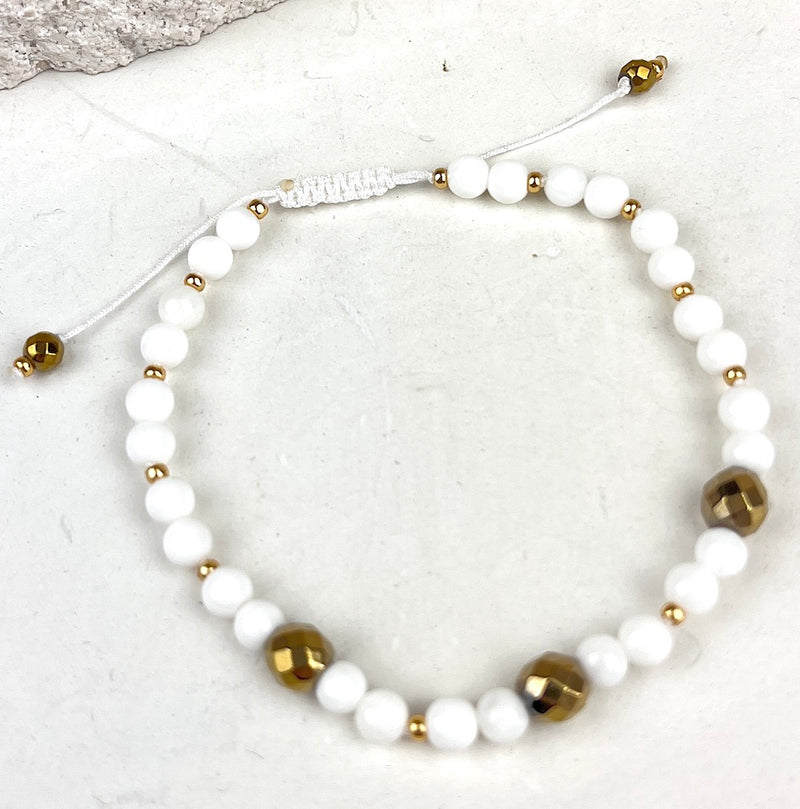 Bracelet with white beads and gold accents on a light background