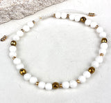 Bracelet with white beads and gold accents on a light background