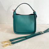 Green leather handbag with a strap on a light background
